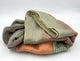 Latacunga alpaca wool throw blanket – a folded, multicolored blanket rests on a plain white surface, displaying hues of green, orange, and brown, with a soft, textured look