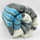 Aychapicho baby alpaca wool blanket – a rolled-up woolen blanket with gray, blue, and white stripes sits against a plain white background