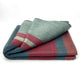 Atacazo baby alpaca wool blanket – a folded red, green, and gray striped blanket rests on a plain white surface, displaying its woven texture and layered patterns