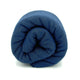 A tightly rolled, dark blue blanket is positioned upright against a plain white background.