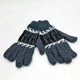 Gray knitted gloves with black and white patterns of reindeer and geometric designs lie flat on a white surface, their fingers aligned and slightly overlapping.