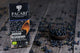 A chocolate box labeled PACARI Premium Organic Chocolate with Andean Blueberry stands on a rustic wooden surface, surrounded by scattered blueberries and a small bowl of them.
