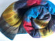Alpaca wool queen blanket – a colorful, multicolored blanket is rolled up, displaying vibrant stripes of red, blue, yellow, and purple. It's lying on a plain white surface