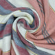 Rucu baby alpaca wool blanket – a spiral of soft, multicolored fabric with stripes of pink, blue, yellow, and gray, intricately folded, creating a textured, cozy appearance