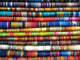 Colorful woven fabrics are stacked in layers, displaying intricate patterns and vibrant hues. They create a visually rich tapestry, likely representing traditional or cultural textile designs.