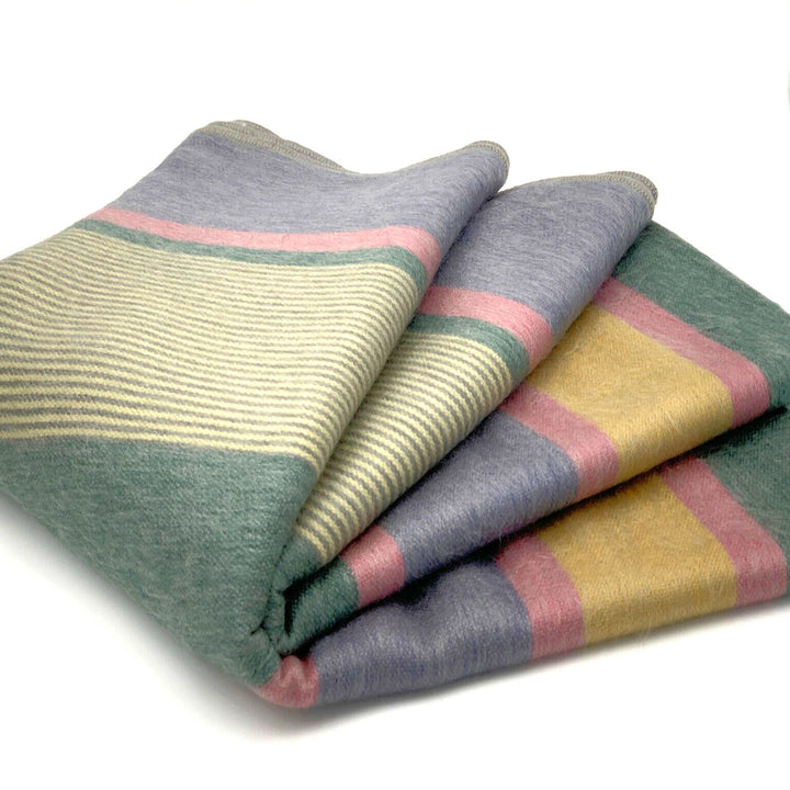 Guagua baby alpaca wool blanket – a folded, striped blanket with muted colors including green, gray, yellow, and pink rests on a white surface, showcasing its soft material and neatly layered edges