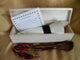 A white wooden box contains a rolled diploma tied with a black band. Beside it, a card with text reads: Crea el yogurt Fotomochis and instructions. A multicolored cord lies outside.