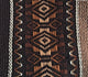 A textile displays intricate, symmetrical diamond patterns in shades of brown, beige, and black, with alternating geometric designs, creating a rich, decorative texture in a woven fabric.