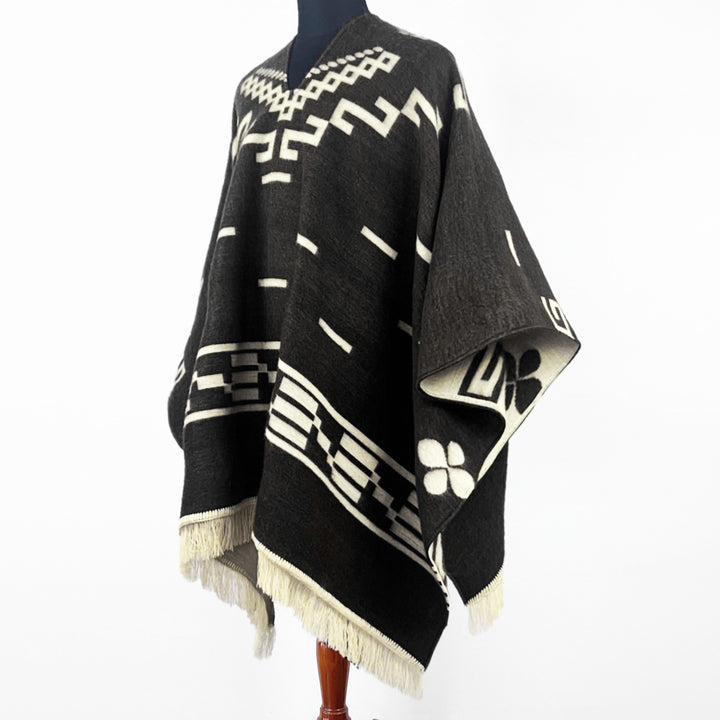 Clint Eastwood alpaca wool poncho – a black poncho with white geometric patterns and fringed edges is displayed on a mannequin against a plain white background