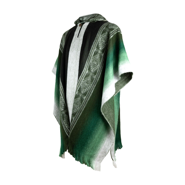A green poncho with black and white geometric patterns drapes elegantly on a mannequin, set against a plain white background.