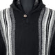 A woolen poncho featuring black, gray, and white vertical stripes. It has a button at the neck and is set against a plain backdrop.