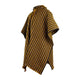 A woven poncho displays diagonal yellow, black, and white stripes with fringed edges and a hood, hanging in a simple, white, unembellished background.