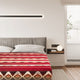 A bed with a geometric patterned red blanket rests in a modern, minimalist bedroom. Soft lighting and a nightstand with a globe lamp complement the serene atmosphere.