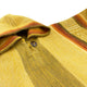 Hooded yellow wool garment with a wooden button; displays stripes in rust and olive tones, and a geometric pattern. The texture appears soft, set against a plain background.