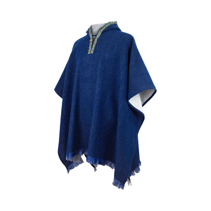 A blue poncho with fringed edges and an embroidered collar with geometric patterns is displayed on a plain, white background.