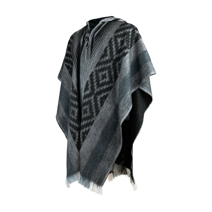 Nambija lightweight alpaca wool hooded poncho – a wool poncho with a black and gray geometric pattern hangs in a well-lit space, featuring a woven texture and fringe at the edges
