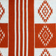 A patterned textile displays alternating rust-red geometric designs and vertical stripes against a cream background, creating a repetitive symmetrical pattern. The fabric texture suggests softness and warmth.