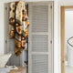 A patterned blanket hangs over a beige cabinet with lattice doors in a modern, minimalist room featuring light wood accents and neutral tones.