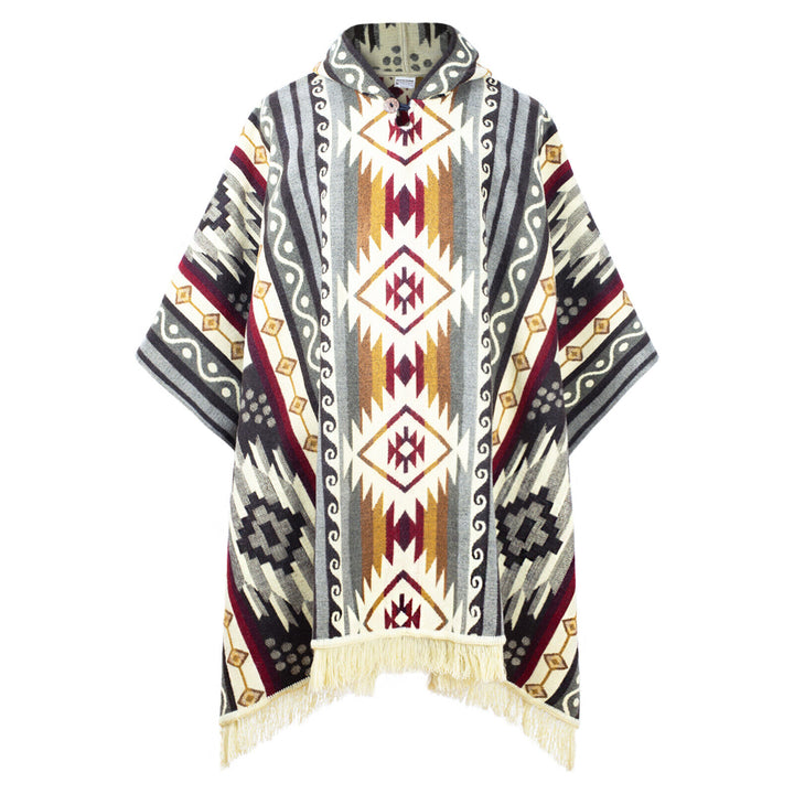 A colorful poncho features geometric patterns in red, grey, and cream, with fringe at the bottom edge. It hangs against a plain white background, emphasizing its intricate design.