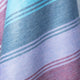 Tinizaray baby alpaca wool blanket – a woven textile displays curved stripes in shades of blue, purple, and red, creating a soft, flowing pattern and texture