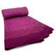 Chontamarca baby alpaca wool blanket – a magenta wool blanket is rolled at one end, with layered folds visible. It rests on a white surface, showcasing its warm and vibrant texture