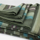 Jambue baby alpaca wool blanket – a folded woolen blanket features green, blue, and purple stripes. It is neatly arranged on a flat surface, showcasing its soft texture and detailed weaving