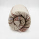 Zhumir baby alpaca wool blanket – a rolled-up, multicolored striped blanket rests against a plain white background, showcasing soft beige, brown, and gray hues, creating a cozy and inviting appearance