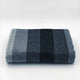 Gullian baby alpaca wool blanket – a folded wool blanket displays horizontal stripes in varying shades of gray. It rests on a plain white surface, highlighting the texture and color contrast