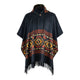 A dark poncho features colorful geometric patterns and fringed edges, with a button at the neck. It hangs against a plain, white background.