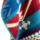 A colorful woven textile, featuring geometric patterns in red, blue, and turquoise, drapes with visible texture against a white backdrop.