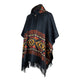 Poncho with vibrant geometric patterns drapes elegantly, featuring fringed edges and a buttoned neck. The design includes reds, yellows, and oranges, surrounded by Greek key motifs in a room with neutral colors.