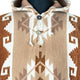 A hooded poncho with geometric patterns is adorned with brown and white zigzag designs. Fastened by two buttons, it rests on a neutral mannequin.