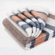 Sopoto baby alpaca wool blanket – a neatly folded blanket, featuring horizontal stripes in shades of blue, orange, and brown, rests against a plain white background, showcasing its textured fabric