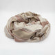 Zhumir baby alpaca wool blanket – a soft, beige blanket with brown and gray stripes is crumpled on a plain white surface, creating a casual, textured pattern