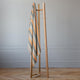 Tumbunuma baby alpaca wool blanket – a wooden clothes rack holds a striped blanket with gray and orange colors. The context is a room with light gray walls and a parquet wood floor