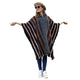 A person wearing a patterned poncho stretches their arms outward. They are wearing a hat, sunglasses, and sneakers, standing against a plain white background.