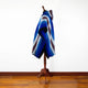 Wuachapa llama wool hooded poncho – a striped blue and brown poncho hangs on a wooden stand, displayed against a white wall and wooden floor for visual contrast