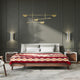 Bed adorned with patterned quilt, situated in a modern bedroom. The setting features geometric pendant lights, wall sconces, and side tables, all against a dark-colored wall backdrop.