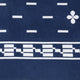 A patterned fabric displays white geometric shapes, including rectangles and a floral motif, on a dark blue background with a checkerboard stripe design near the bottom.