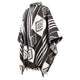 A black and white patterned poncho, featuring geometric designs and stripes, drapes elegantly with fringed edges. It's displayed against a plain white background.
