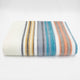 Nongora baby alpaca wool blanket – a folded colorful blanket displays horizontal stripes in orange, blue, gray, and yellow, resting on a plain white surface in a minimalist setting