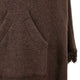 A brown woolen fabric features a large, centered pocket with visible stitching. To the right, fringed edges suggest a textile or garment context. No text is present.
