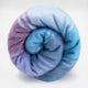 Tinizaray baby alpaca wool blanket – a soft, multicolored blanket with blue and purple hues is tightly rolled, displaying its fluffy texture against a plain white background