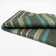 Jambue baby alpaca wool blanket – a folded blanket showcases olive green, teal, and purple stripes, resting on a plain white surface