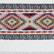 A woven textile features geometric diamond and zigzag patterns in brown, red, and green, flanked by black and white Greek key motifs, set against a white background.