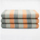 Tumbunuma baby alpaca wool blanket – three folded blankets, displaying a pattern of gray, orange, and light beige stripes, are stacked neatly against a plain white background