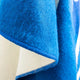 A close-up of a blue, fuzzy fabric drapes with visible stitching, highlighting texture and edge details. White lining is partially visible, providing contrast, suggesting a textile or clothing item.
