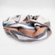 Sopoto baby alpaca wool blanket – a striped blanket with orange, blue, white, and gray colors lies loosely bundled. It rests on a plain white background, presenting a soft and cozy appearance