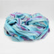 Tzacantza baby alpaca wool blanket – a soft blanket lies crumpled, showcasing pastel blue, purple, and green stripes. It rests on a plain white surface, highlighting its cozy texture and colorful pattern