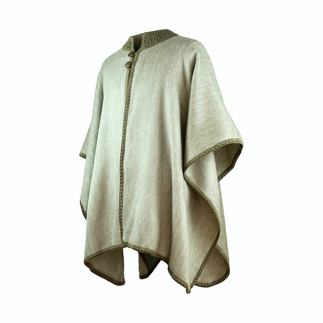 A light brown wool cape with decorative trim and two buttons hangs in a neutral space, showcasing its flowing, draped design.